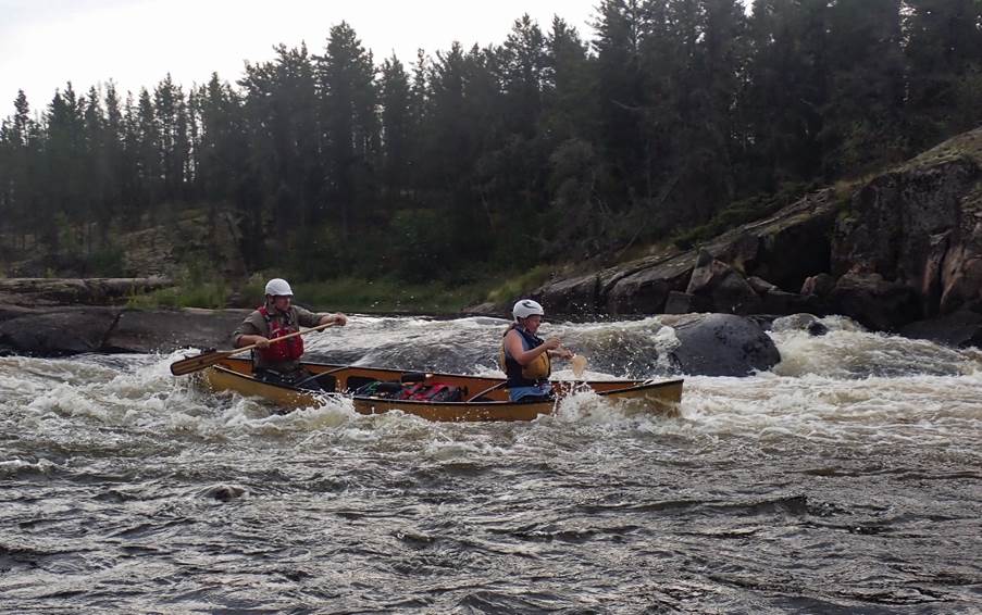 A couple of people in canoes on a river

Description automatically generated