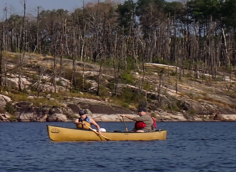 A couple of people in a canoe on a lake

Description automatically generated