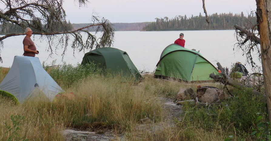 Two tents next to a lake

Description automatically generated