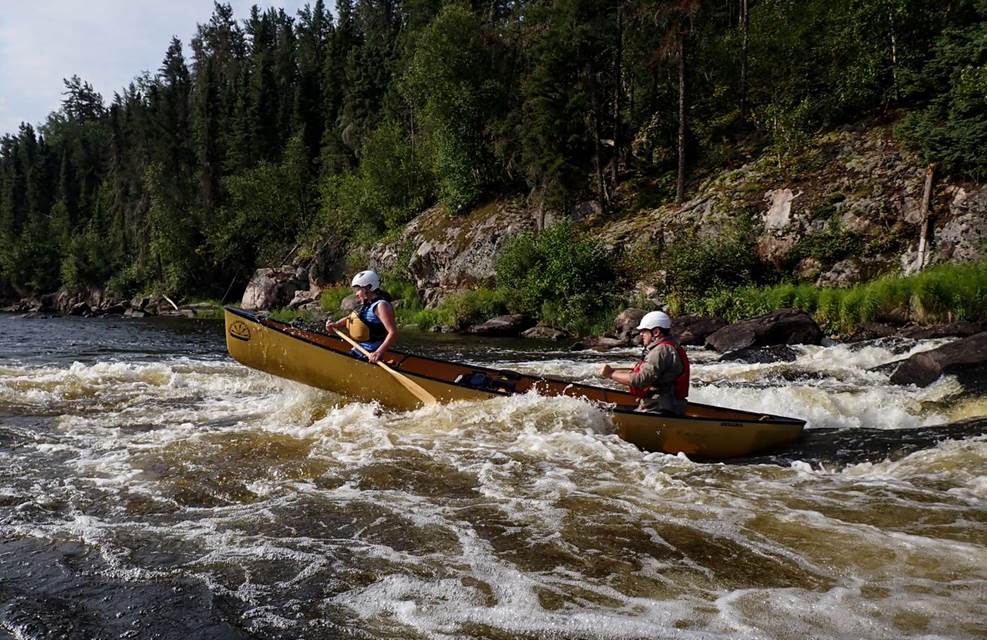 A couple of people in a canoe on a river

Description automatically generated