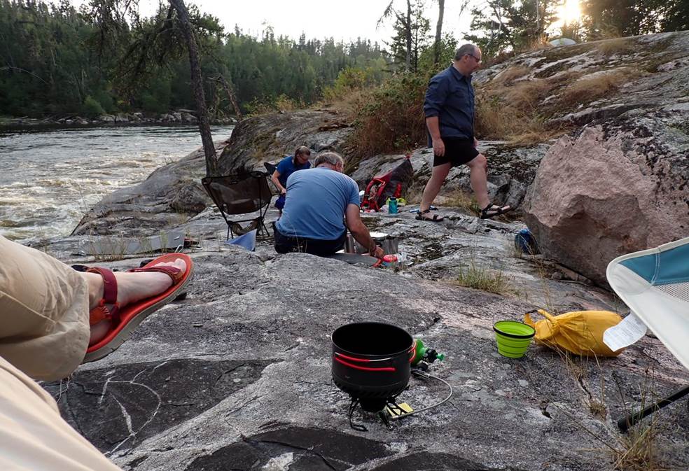 A group of people sitting on a rock by a river

Description automatically generated