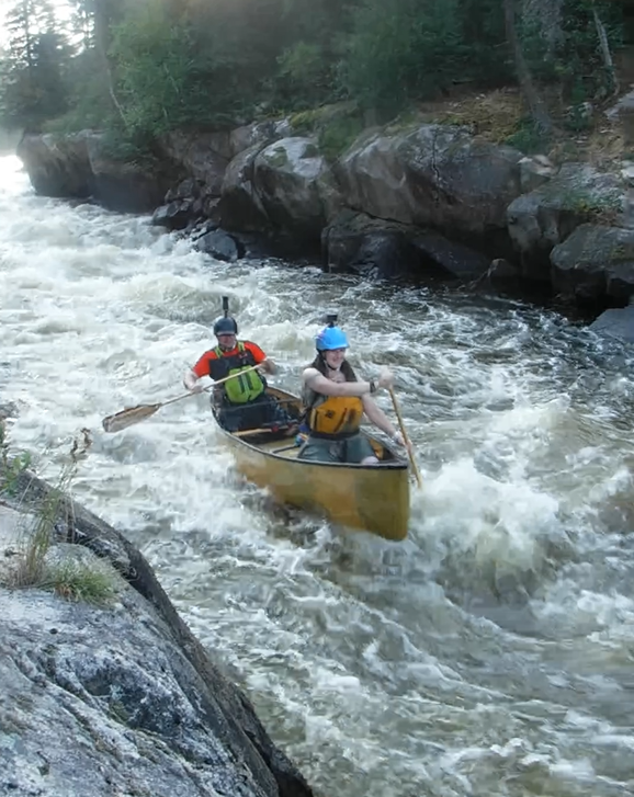 A couple of people in a canoe on a river

Description automatically generated