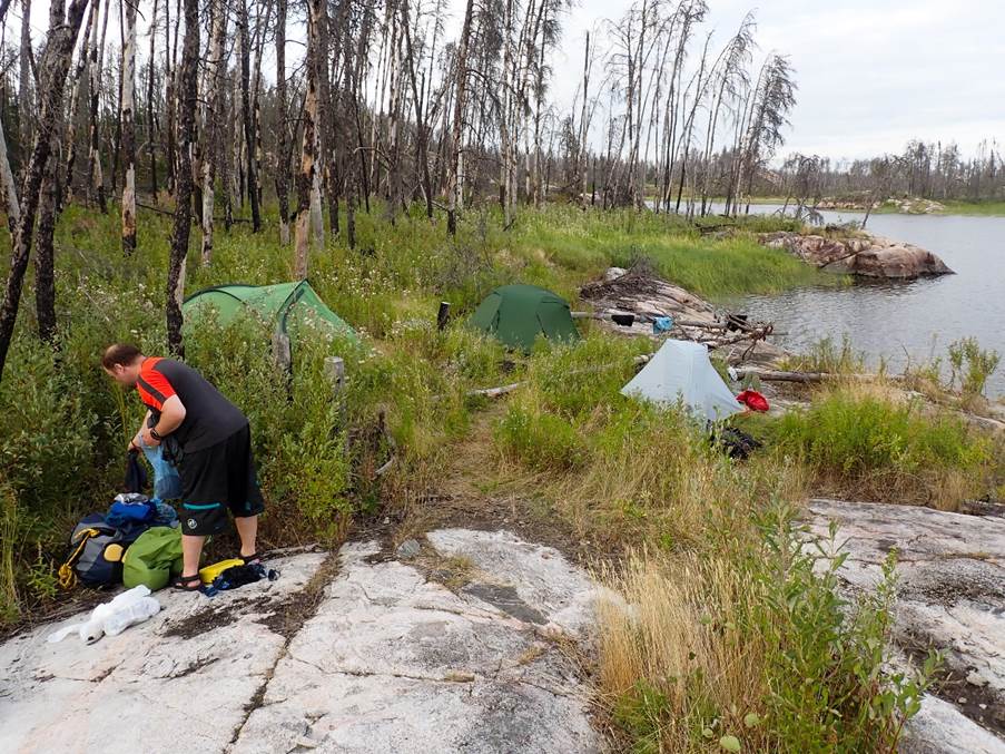 A person standing next to tents by a body of water

Description automatically generated