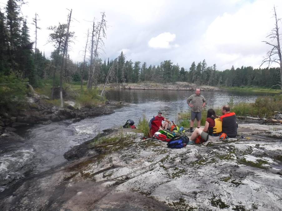 A group of people sitting on a rocky shore

Description automatically generated