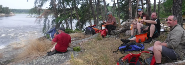 A group of people sitting on a hill near a lake

Description automatically generated