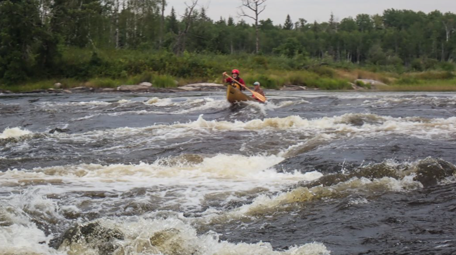 A group of people in a canoe in a river

Description automatically generated