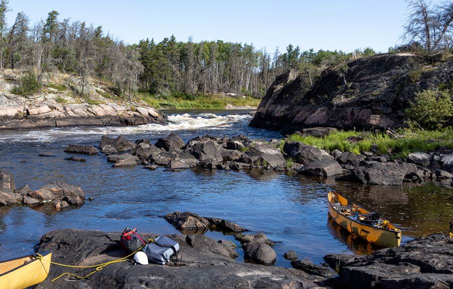 A river with rocks and a boat

Description automatically generated