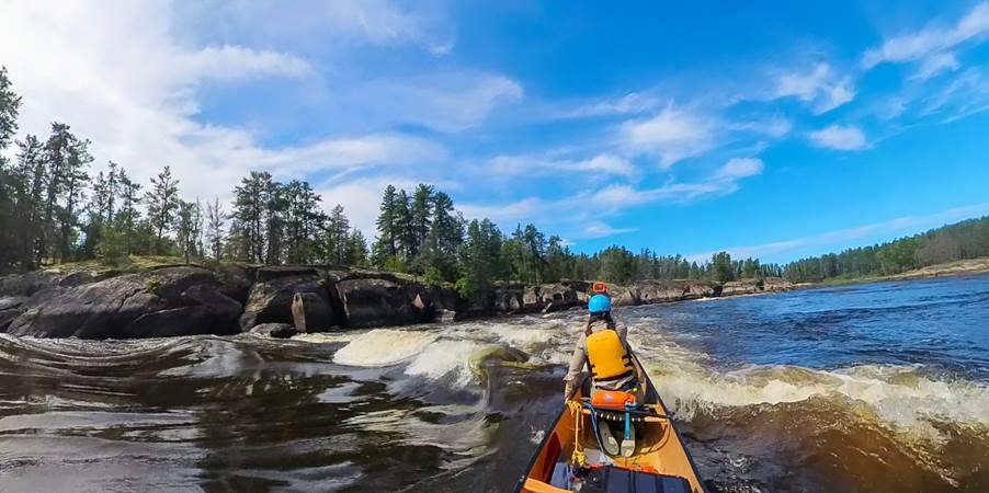 A person in a canoe on a river

Description automatically generated