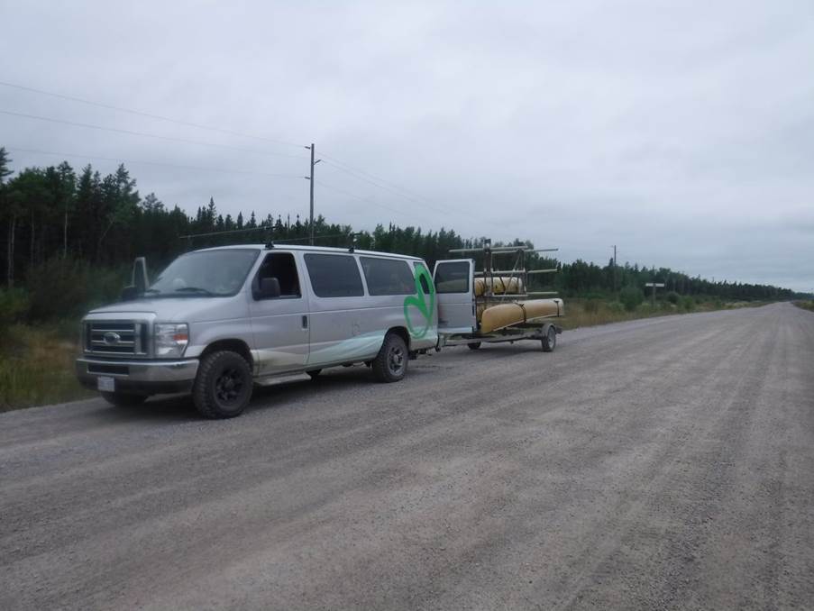 A van with a trailer on the side of the road

Description automatically generated