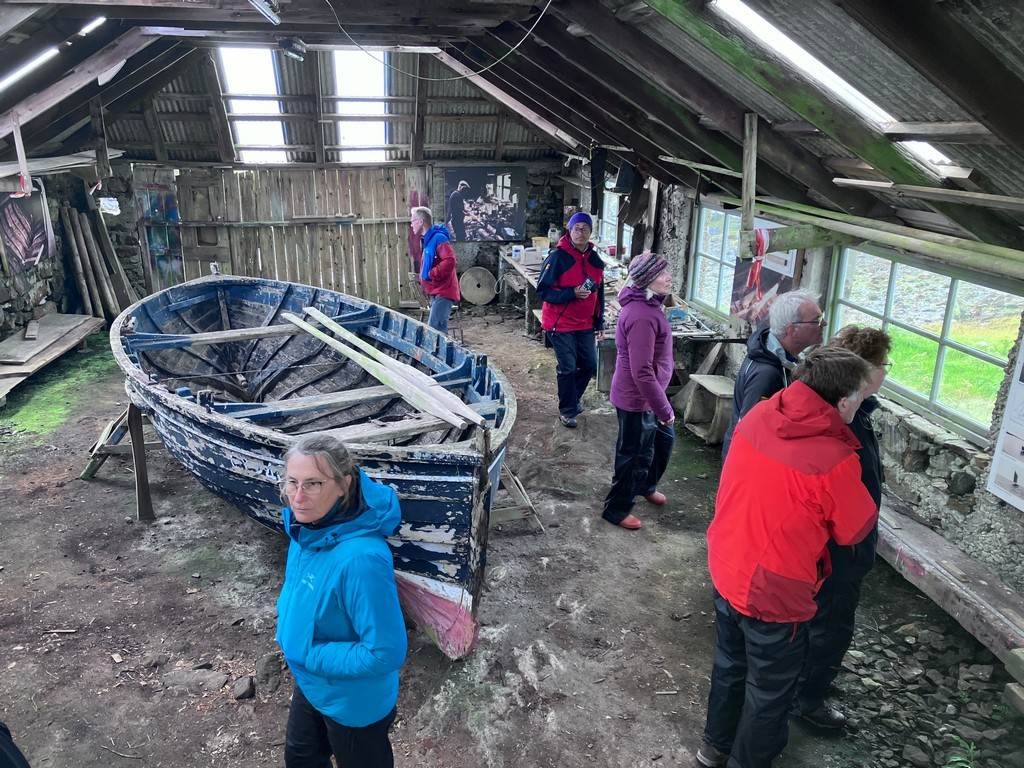 A group of people standing around a boat in a shed

Description automatically generated