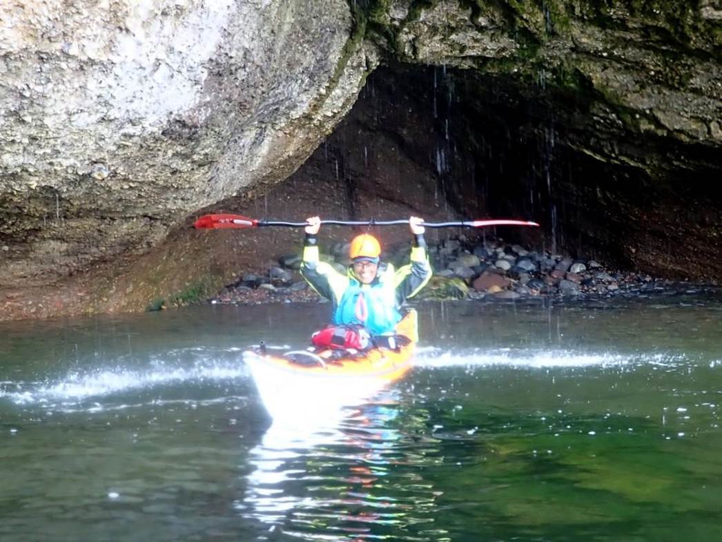 A person in a kayak under a cave

Description automatically generated