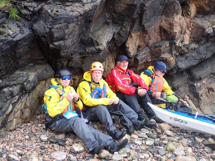 A group of people sitting on rocks

Description automatically generated