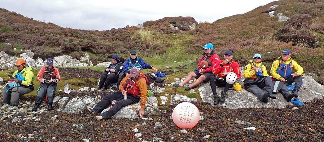 A group of people sitting on rocks

Description automatically generated
