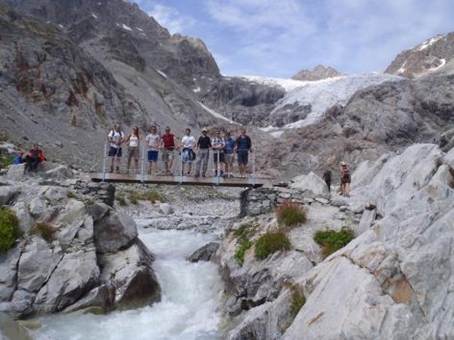 A group of people standing on a bridge over a river

Description automatically generated
