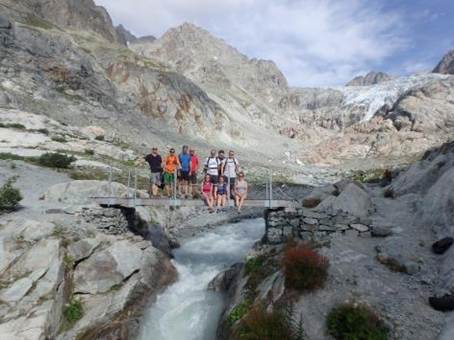 A group of people standing on a bridge over a river

Description automatically generated