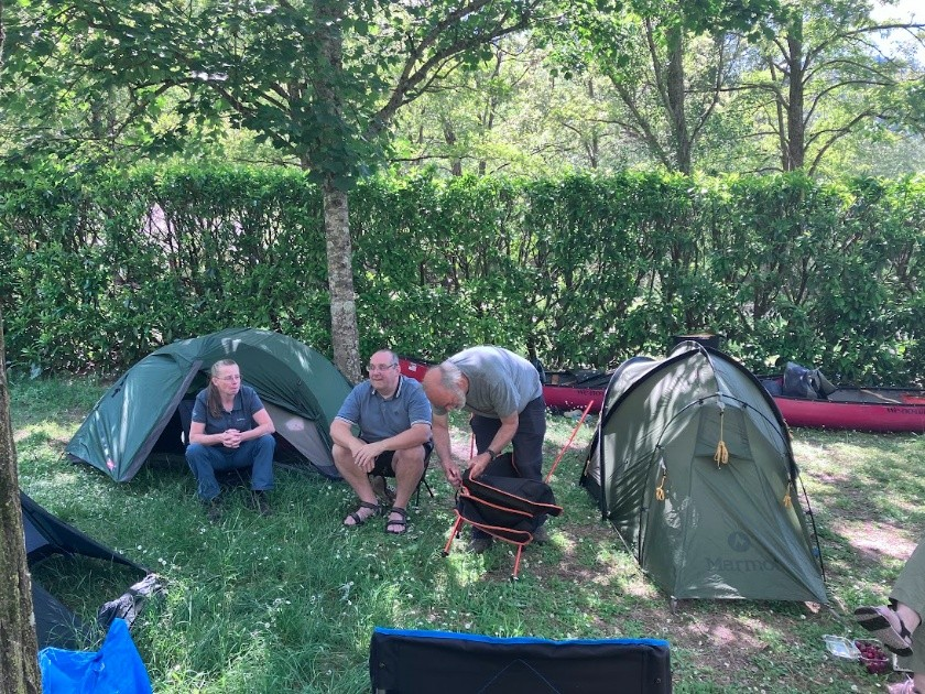 A group of people sitting next to tents

AI-generated content may be incorrect.