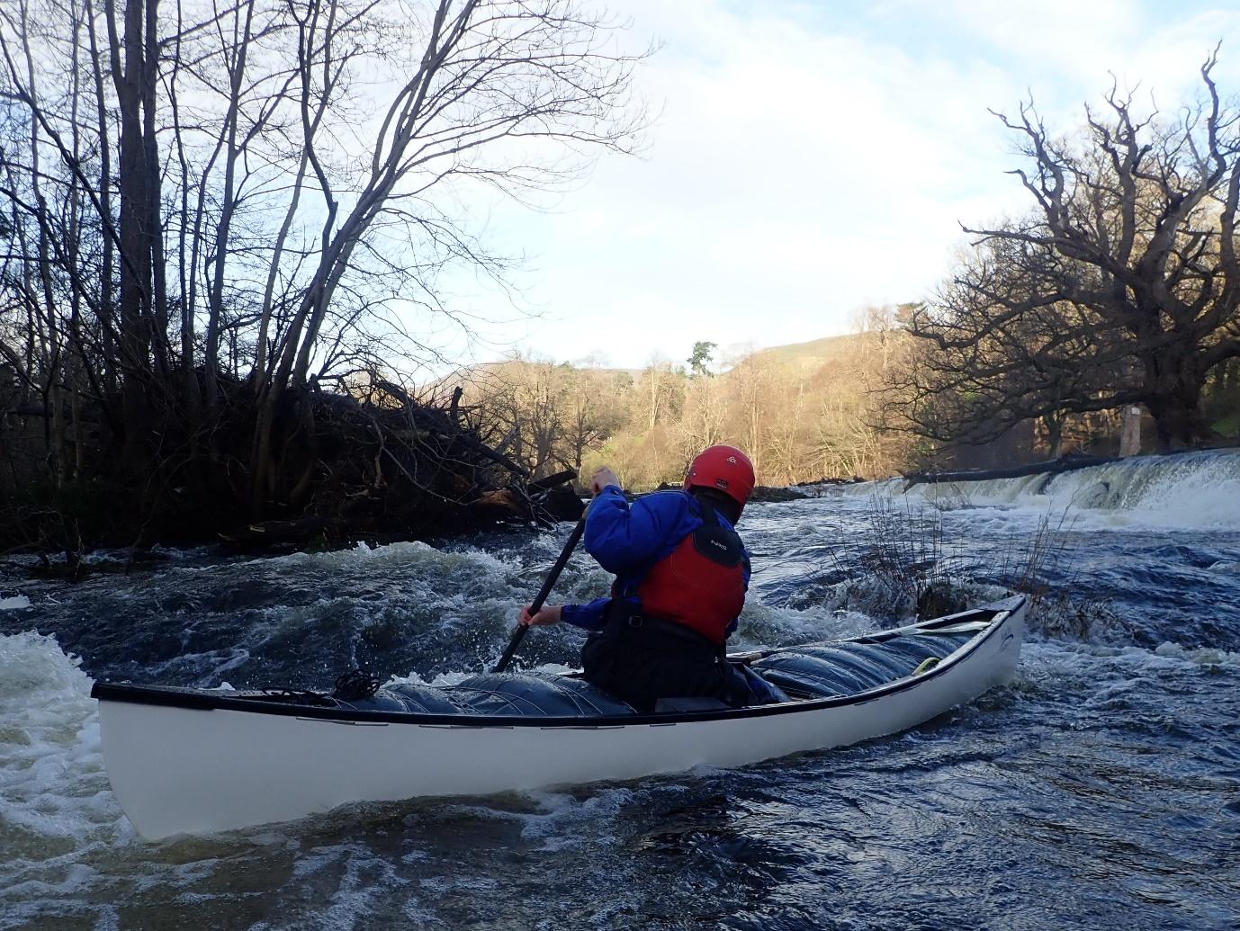 A person in a kayak on a riverDescription automatically generated with medium confidence