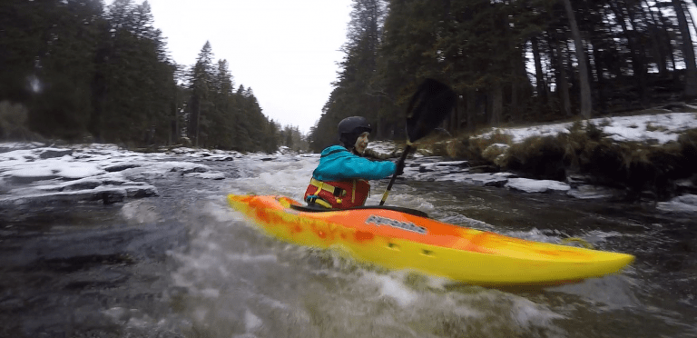 A person in a kayak on a river Description automatically generated with low confidence
