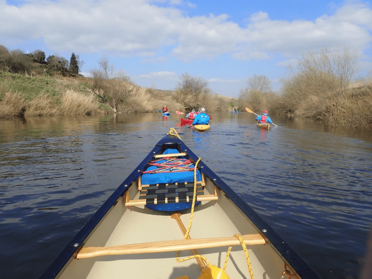 A group of people in a boat on a river Description automatically generated with low confidence