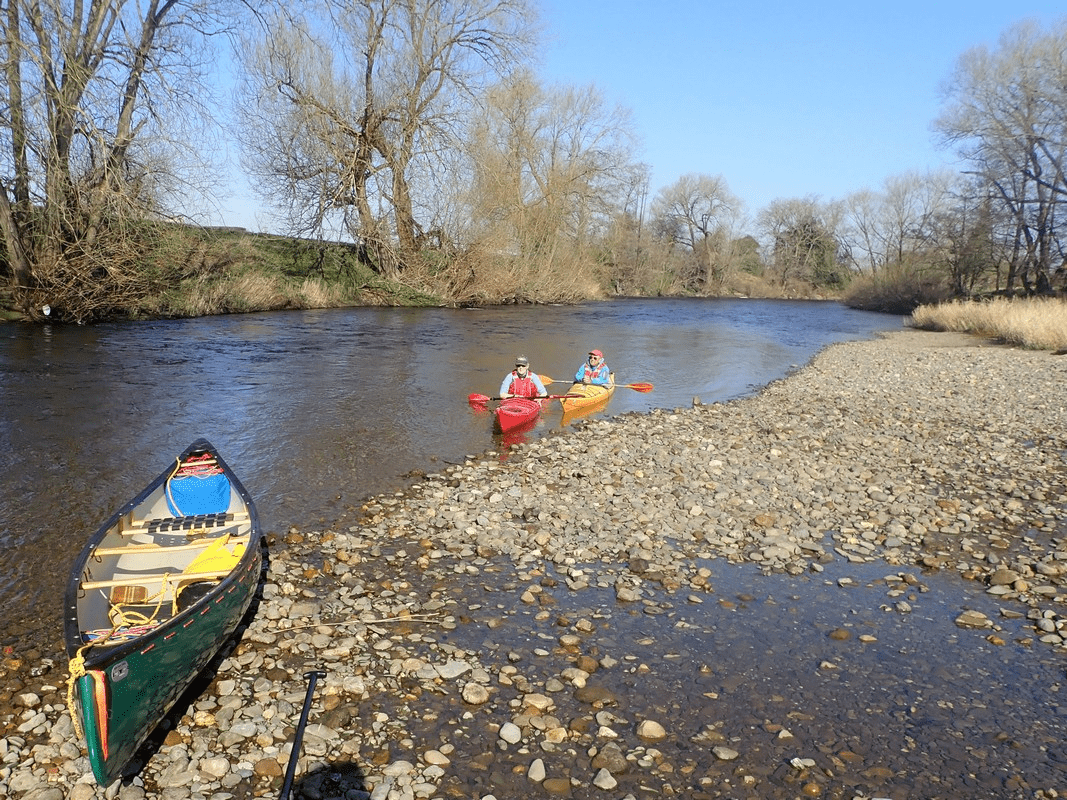 A group of people in kayaks on a riverDescription automatically generated with medium confidence