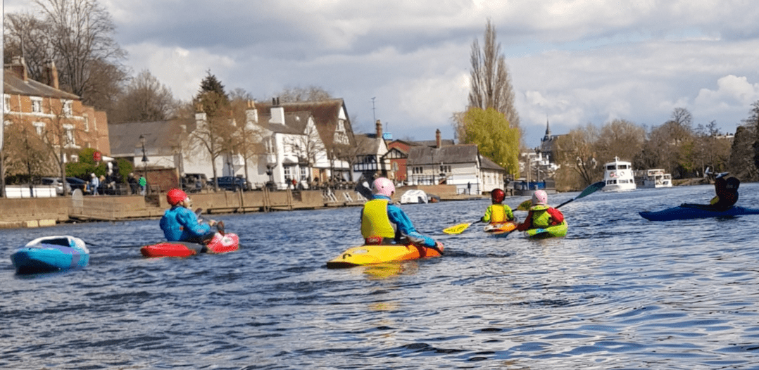 A group of people in kayaks on a body of waterDescription automatically generated with medium confidence