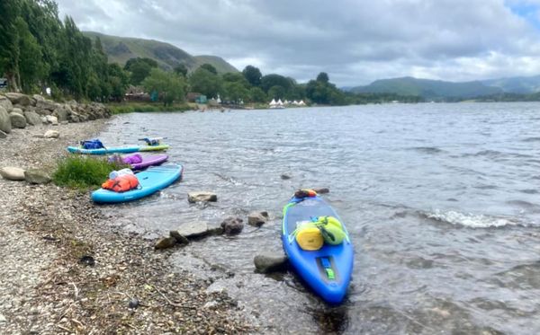 A body of water with boats on it and trees in the backDescription automatically generated with low confidence