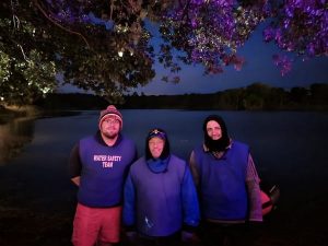 A group of people standing in front of a body of water Description automatically generated with medium confidence