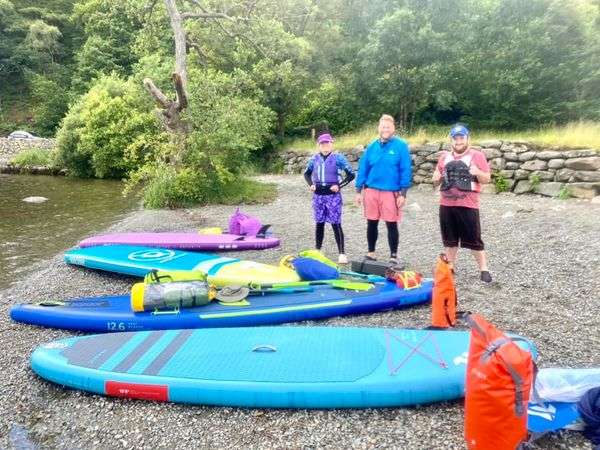 A group of people standing next to kayaks on a beachDescription automatically generated with medium confidence