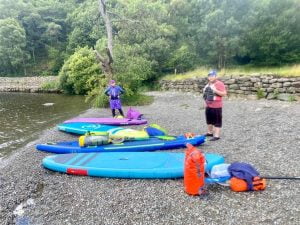 A group of people standing next to kayaks on a river Description automatically generated with low confidence