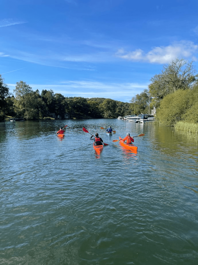 A group of people in a row boat on a riverDescription automatically generated with low confidence