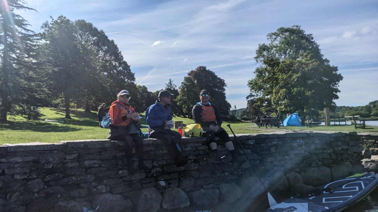 A group of people sitting on a stone wallDescription automatically generated with medium confidence