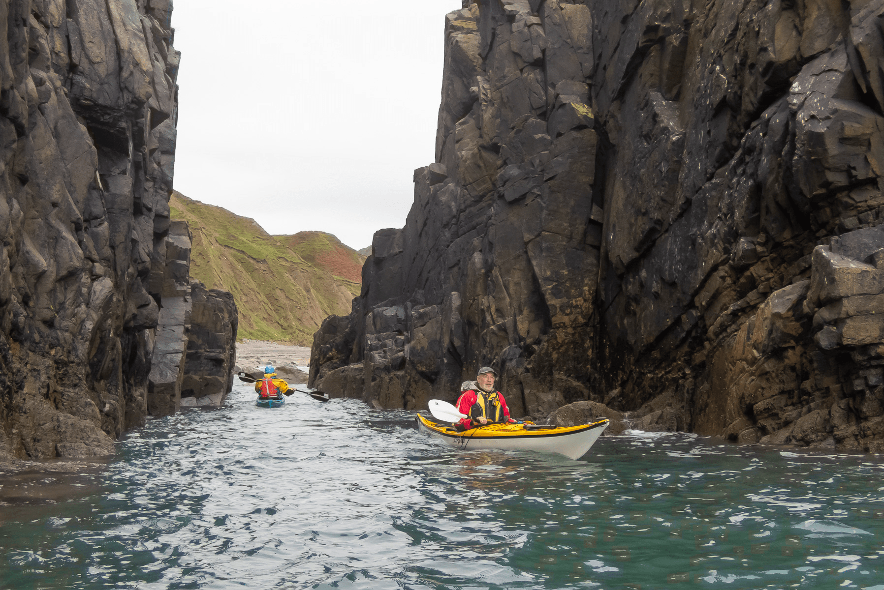 A group of people in a canoe in a river between large rocksDescription automatically generated with low confidence