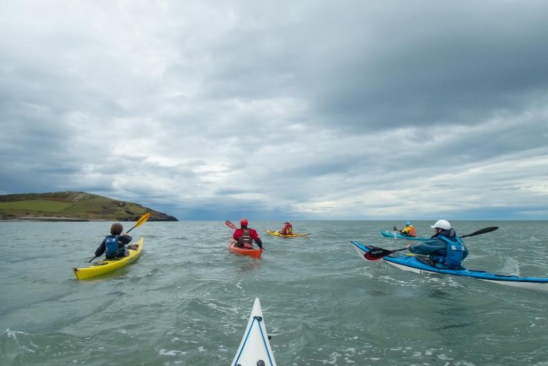 A group of people in kayaks on a body of waterDescription automatically generated with medium confidence