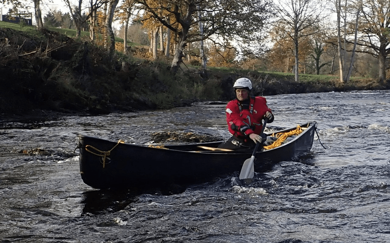 A person in a canoe on a riverDescription automatically generated with medium confidence