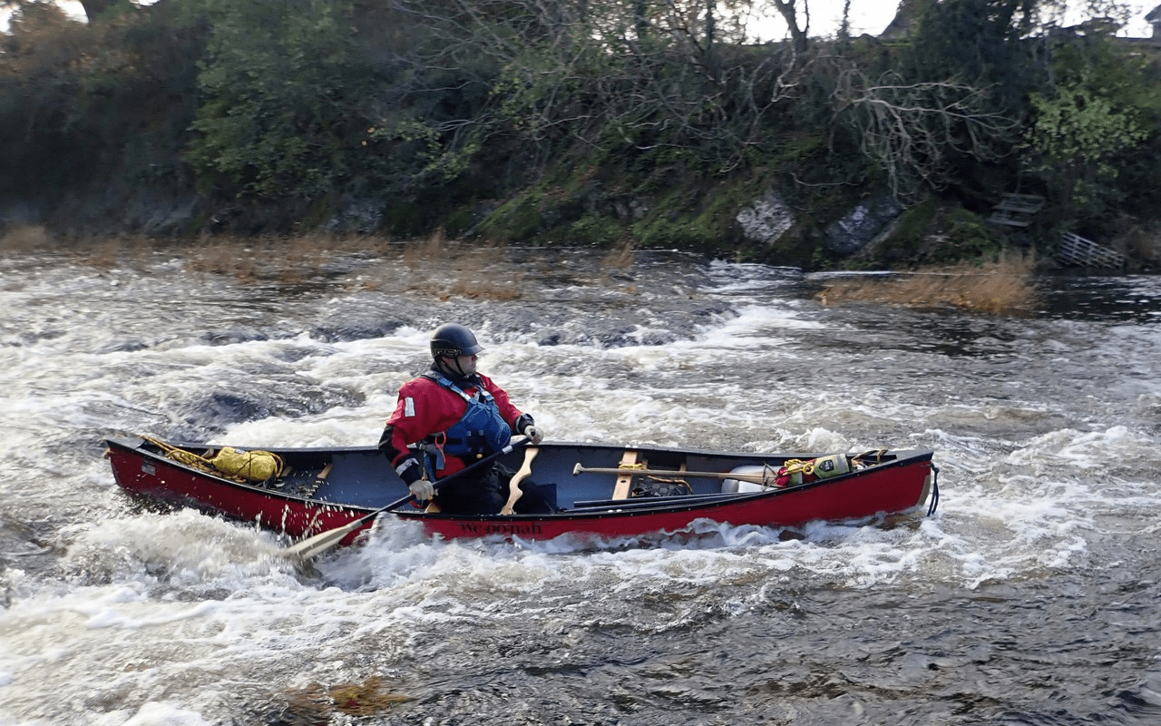 A person in a red kayak on a riverDescription automatically generated with low confidence