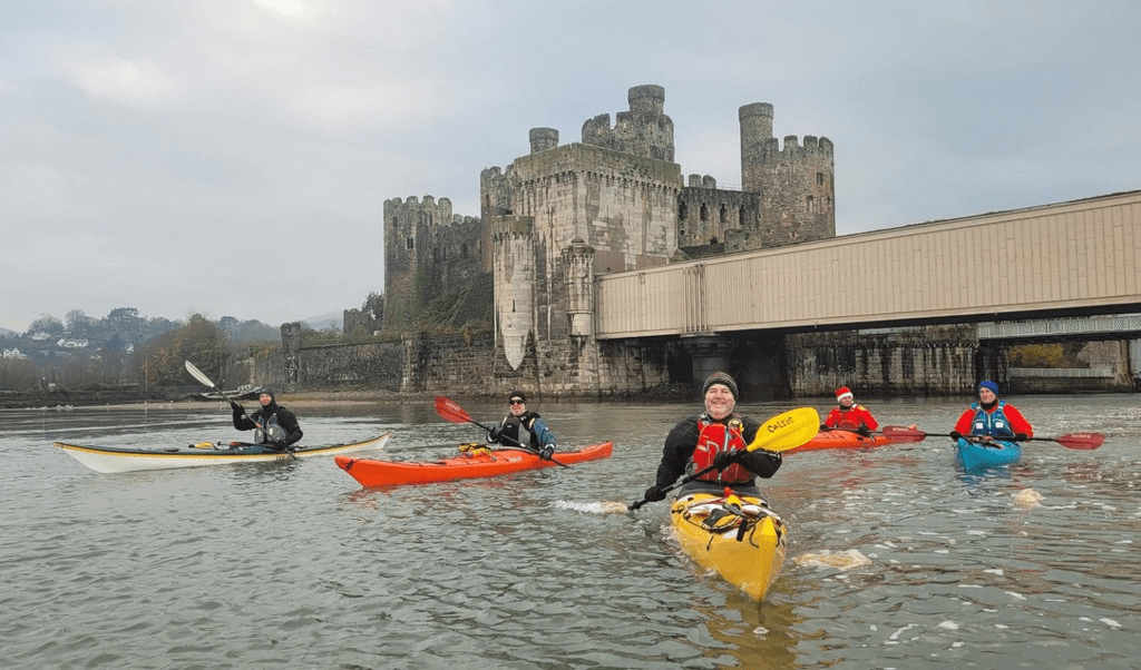 A group of people in kayaks in front of a castleDescription automatically generated with medium confidence
