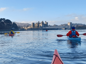 A group of people in kayaks on a lake Description automatically generated with low confidence