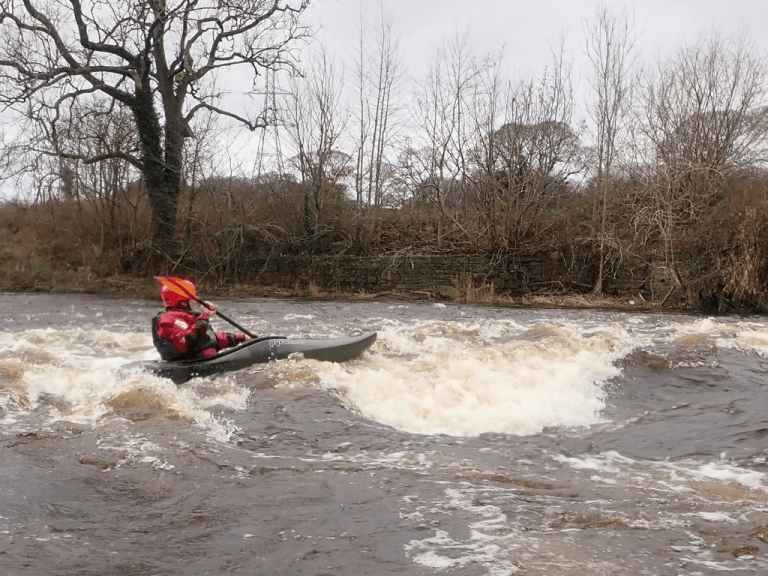 A person in a kayak on a river Description automatically generated with low confidence