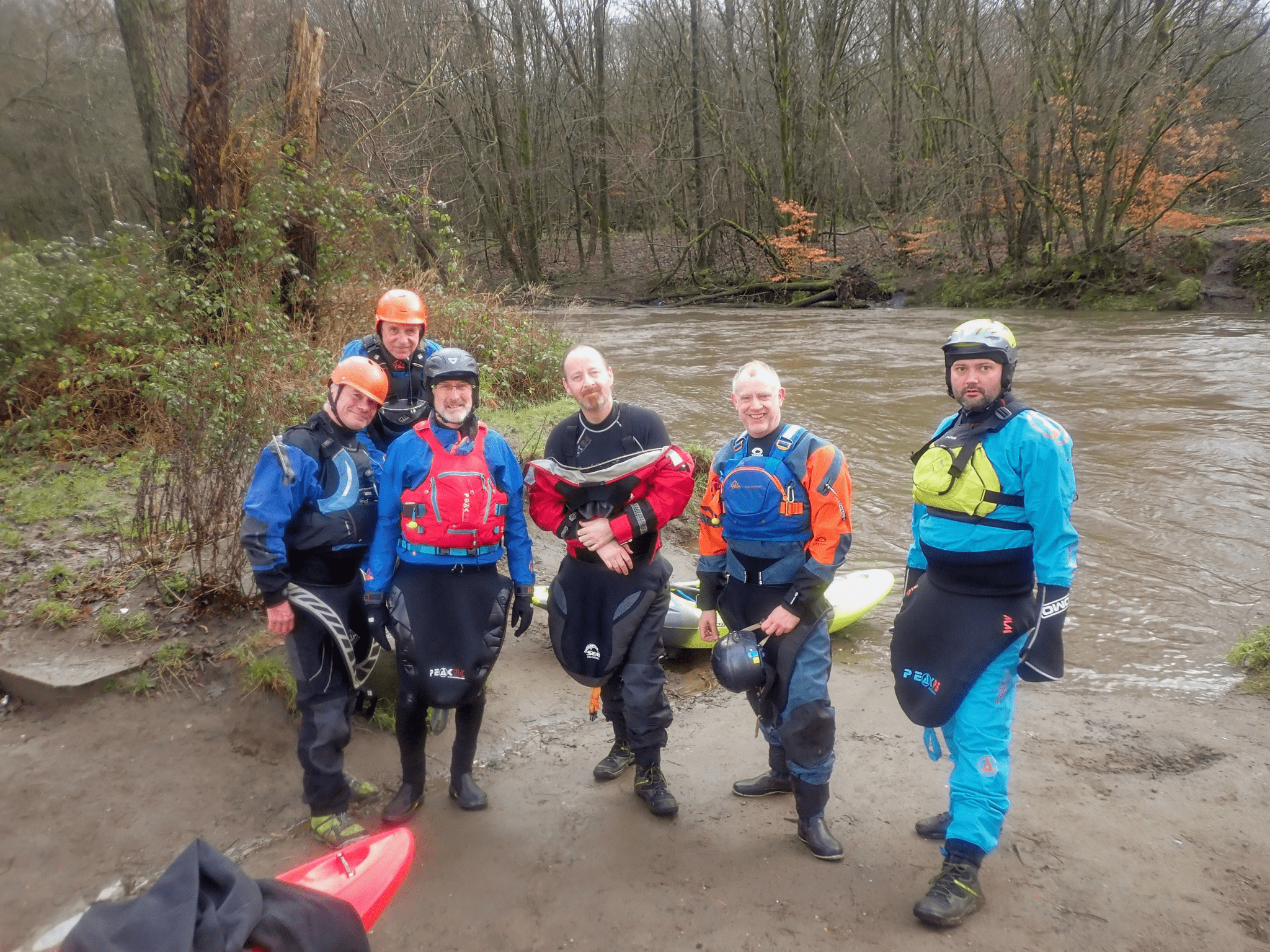A group of people wearing life jackets and standing in a muddy areaDescription automatically generated with low confidence