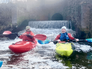 A group of people in kayaks in a river Description automatically generated with low confidence