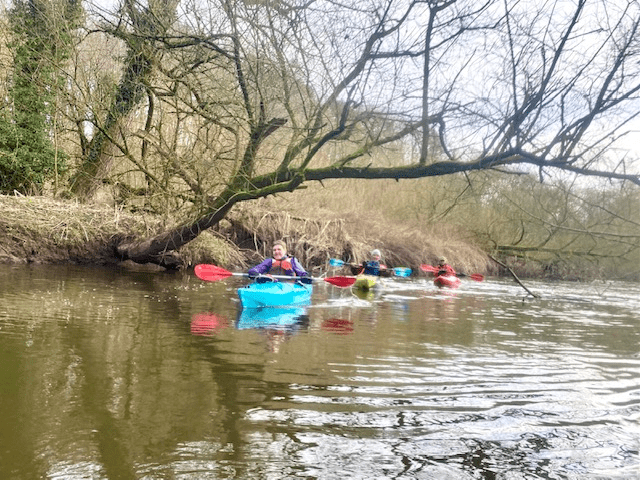 A group of people in kayaks on a riverDescription automatically generated with medium confidence