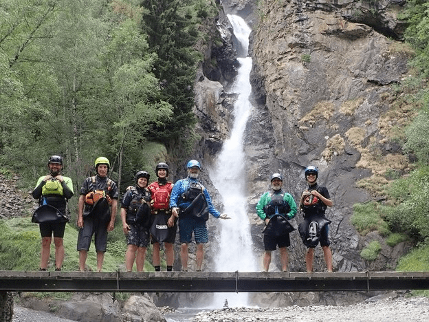 A group of people standing in front of a waterfallDescription automatically generated with medium confidence
