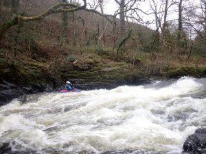 A person in a kayak in a river Description automatically generated with low confidence