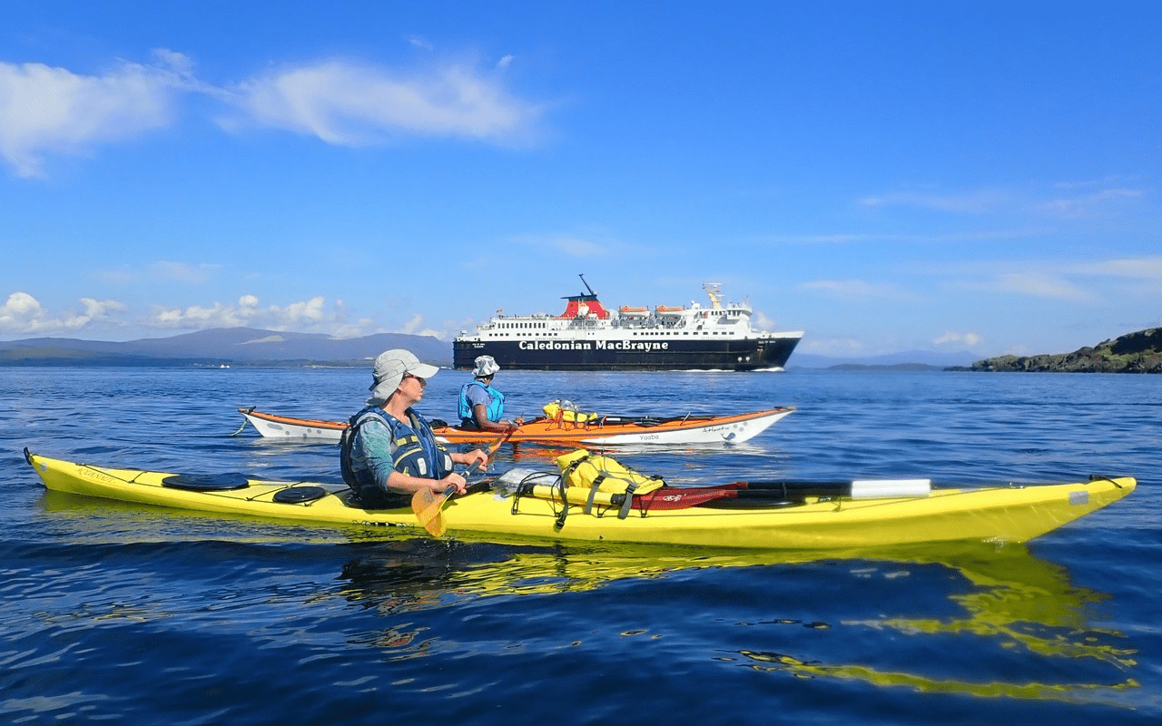A person in a kayak with a boat in the backgroundDescription automatically generated with low confidence