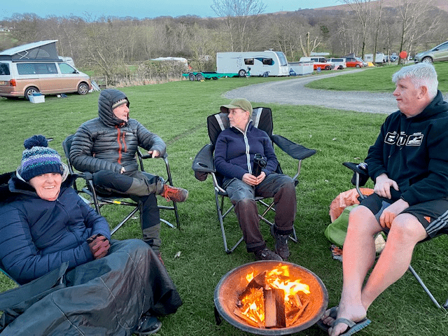 A group of people sitting around a fire
Description automatically generated with medium confidence