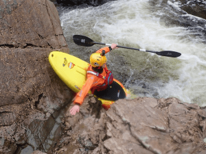 A person in a kayak in a river Description automatically generated with medium confidence