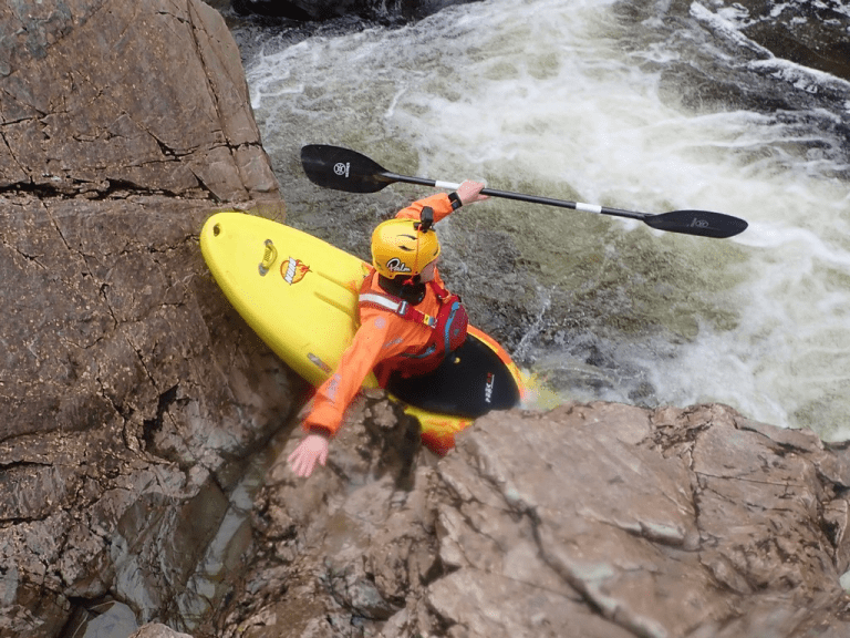A person in a kayak in a river Description automatically generated with medium confidence