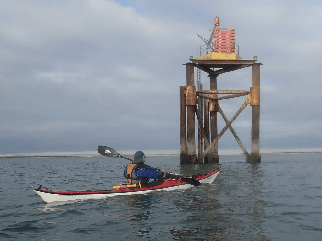 A person in a kayak in front of a structure in the water

Description automatically generated with medium confidence