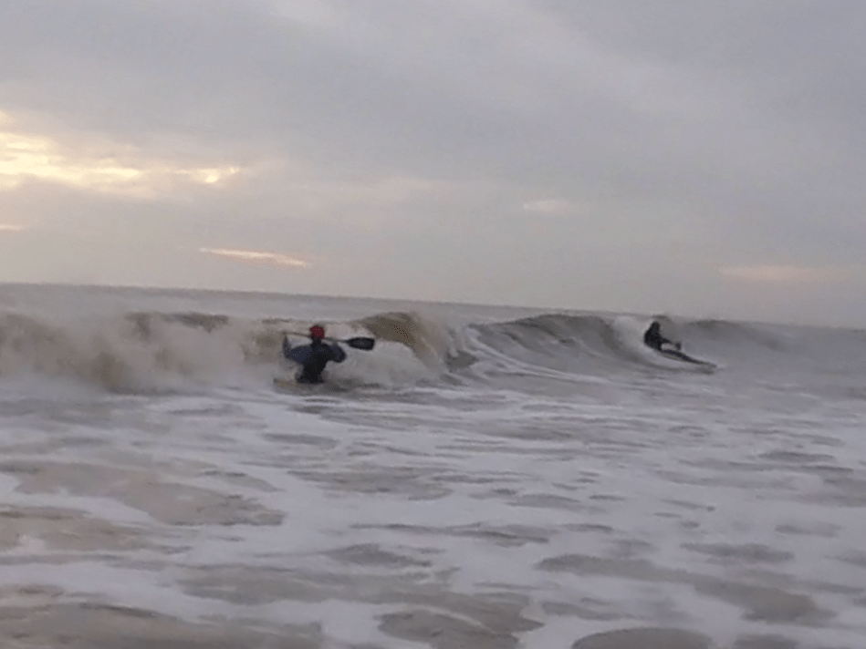 Surfers riding a waveDescription automatically generated with medium confidence