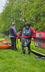 A group of people standing next to kayaks Description automatically generated with low confidence